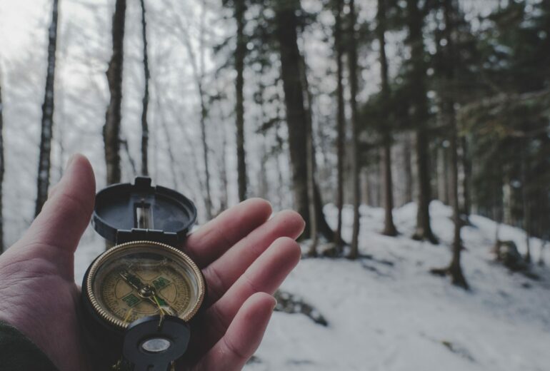 personal holding a compass in the woods